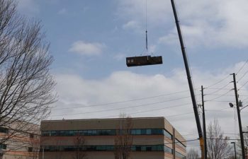 Big crane moving industrial HVAC unit.