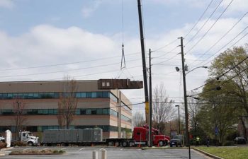 Big crane moving industrial HVAC unit.