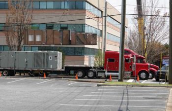 Trucks with industrial HVAC units. Big crane moving HVAC unit.