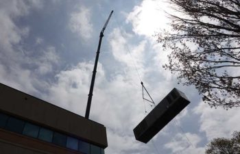 Big crane moving industrial HVAC unit.