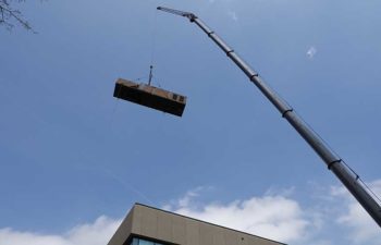 Big crane moving industrial HVAC unit.