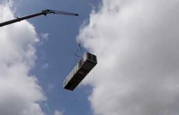 Big crane moving industrial HVAC unit.
