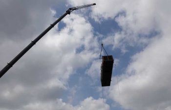 Big crane moving industrial HVAC unit.