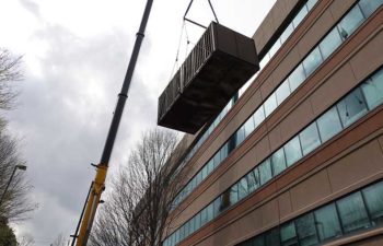 Big crane moving industrial HVAC unit.