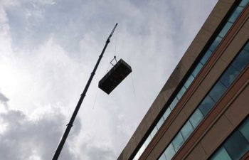 Big crane moving industrial HVAC unit.